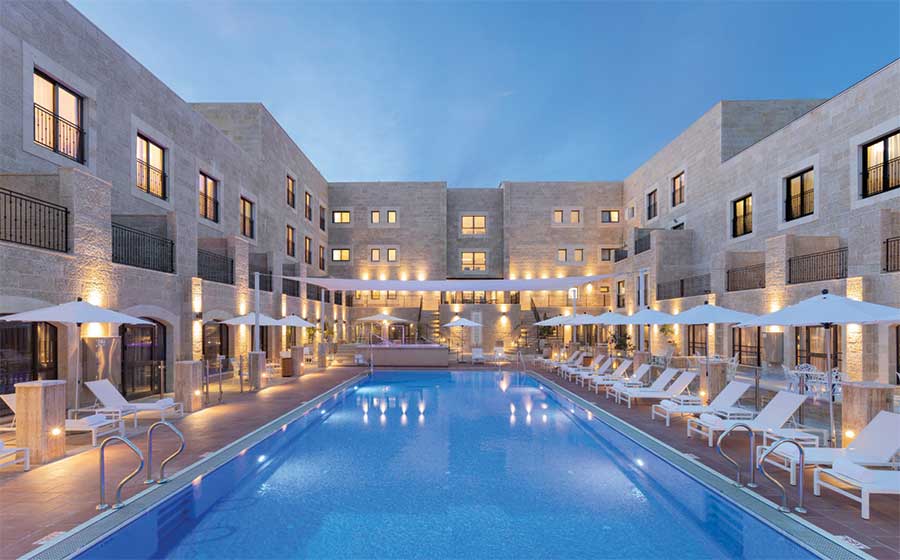 מבנה מלון אדמונד ראש פינה מקיף את חצר המלון ואת בריכת השחייה שמימיה חמימים בכל ימות השנה